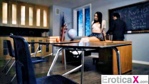 Naughty brunette student in tiny plaid skirt and crop top teases on classroom desk