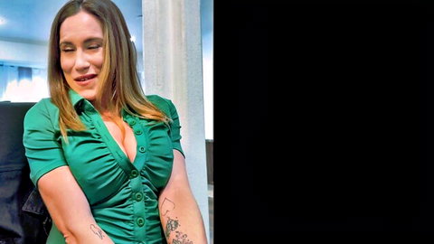 Blonde woman in low-cut green dress showing cleavage and arm tattoo, smiling seductively