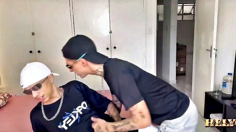 Two tattooed Latino men in caps and casual wear, intimate crotch touch