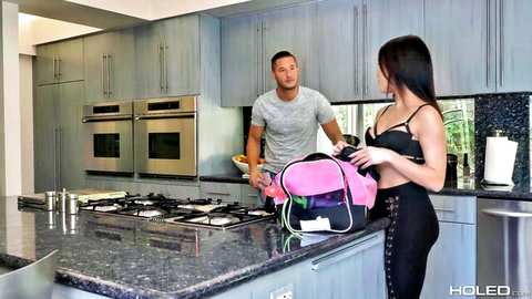 Petite brunette Megan Rain in black lingerie holding pink backpack with man in kitchen