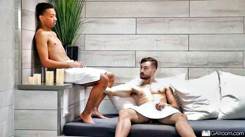 Two fit shirtless men in towels at bathhouse, teasing encounter