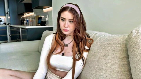 Rosie Rider in white crop top and shorts, seductive pose on couch