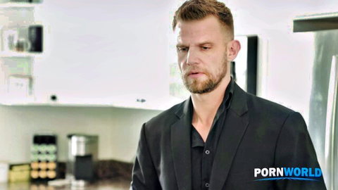 Handsome bearded man in black suit stands intently in modern kitchen