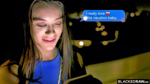 Young tanned blonde in tight blue dress smiles at flirty vacation text on phone