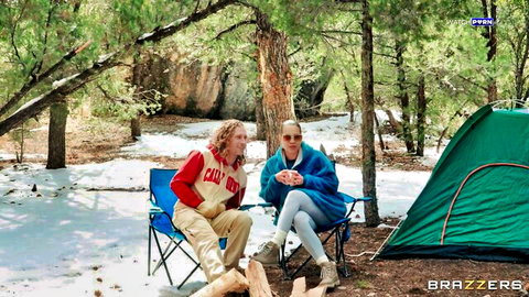 Two sexy women chilling by campfire in snowy outdoor camp near green tent