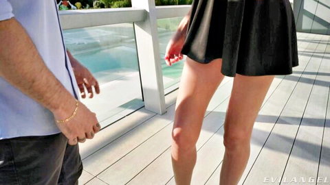 Leggy babe in tiny black skirt teases hunk on balcony by pool