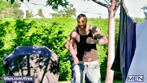 Muscular bearded guy in tank top works rake handle outdoors at MEN.com