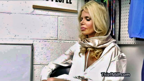 Busty blonde Victoria in shiny V-neck top, seductive backstage pose