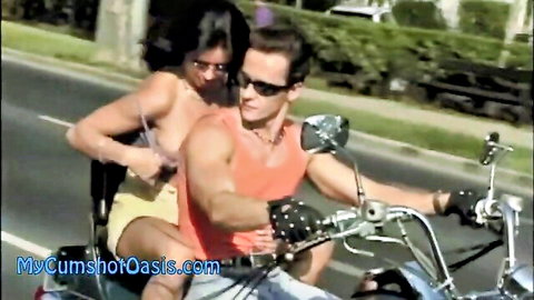 Brunette babe with big tits gropes muscular guy's cock bulge on motorcycle ride