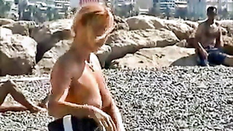 Busty blonde topless on beach with natural tits exposed