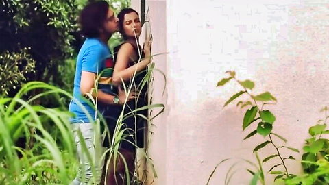Sexy Indian babe in black dress embraced by man outdoors