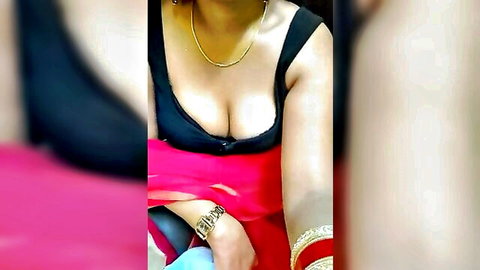 Young Indian babe teasing in low-cut black top and red sari, showing deep cleavage