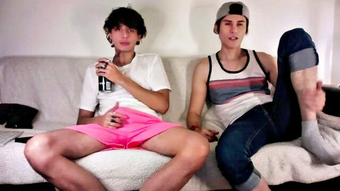 Two young men in casual wear lounging, one in pink shorts from Chaturbate exhibitionist show