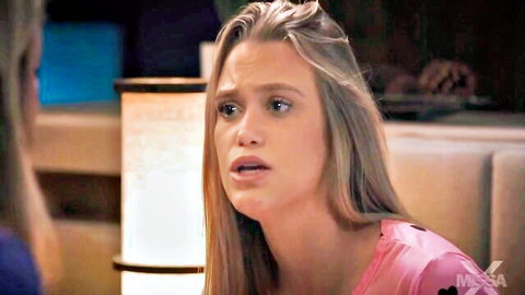 Shocked blonde woman in pink top with open mouth surprised in bedroom scene