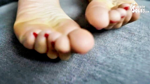 Close-up of sexy bare soles with red painted toenails ready for foot worship