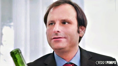 Suited man in office attire holding green bottle looking at camera