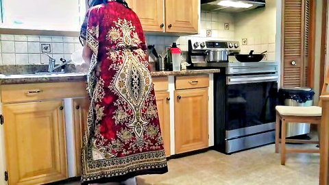 Curvy Indian MILF in flowing red dress bends over kitchen sink teasing her thick ass and bare legs