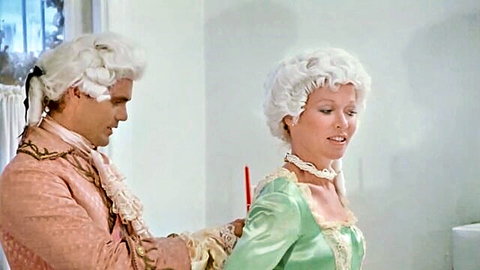 John Holmes in classic vintage period costume with blonde in green dress