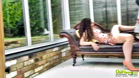 Curvy brunette mature MILF teases with legs spread in pink dress on chaise lounge