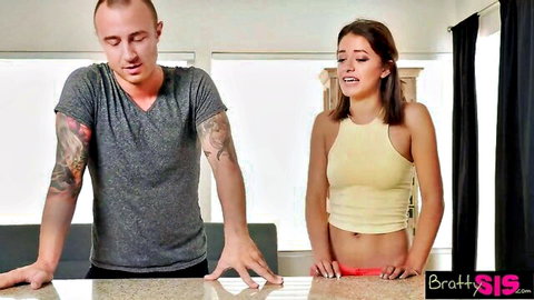 Tattooed stepbrother gestures at skinny brunette stepsister in yellow tank top and red thong in kitchen taboo tease