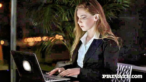 Melissa Benz in white blouse and black blazer typing on laptop at night