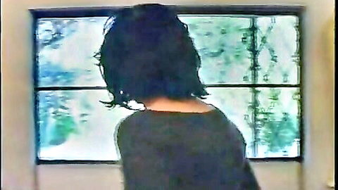 Italian brunette in dark top gazing out window from behind