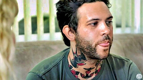 Tattooed man with neck bird tattoos sticks tongue out teasing blonde woman beside him