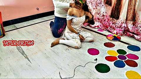 Your Priya in white off-shoulder outfit kneeling during Holi, intimate couple moment