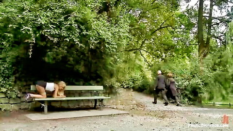 Slim blonde bent over on park bench in public outdoor setting