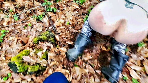 Woman bends over in forest exposing big pale ass in boots and stockings