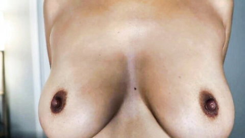 POV closeup of woman's huge bare tits with dark erect nipples and smooth shiny skin