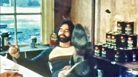 Bearded man relaxing in rustic kitchen with ocean view, vintage style
