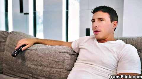 Handsome clothed man lounging on gray couch holding TV remote in modern living room