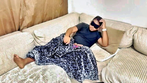 Blindfolded tanned woman masturbating with pink vibrator under leopard blanket on couch