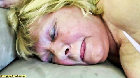Mature blonde granny lying relaxed on bed, eyes closed