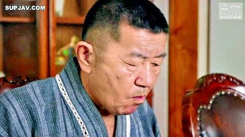 Mature Japanese man in gray kimono sits pensively in traditional wooden room