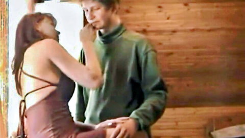 Mature woman in sexy dress intimately touches young man's face in taboo encounter