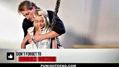 Blonde teen girl in chains embraced from behind by man in BDSM dungeon