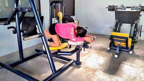 Fit Asian gym girl in pink crop top bending over, teasing hot ass in shorts
