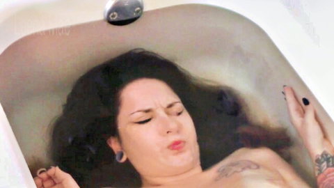 Nude tattooed brunette babe pouting seductively underwater in bathtub solo