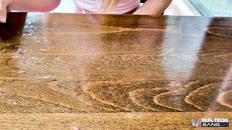 Della Cate in pink top leaning over table in sensual scene with Donnie Rock