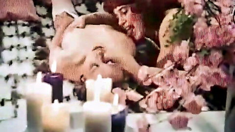 Retro Danish XXX: blonde woman lying nude in pink flowers and candlelight, seductive pose