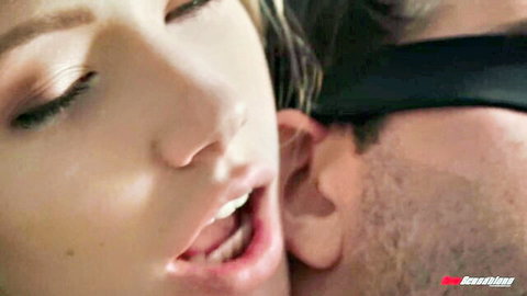 Blonde young mistress teases blindfolded man's ear with open mouth and tongue in intense femdom foreplay