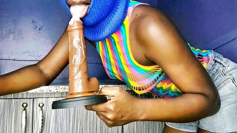Ebony woman in colorful tank top deepthroats big brown dildo suctioned to kitchen counter with saliva dripping.