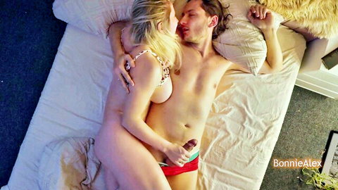 Blonde wife wakes husband with nude embrace, kissing neck and hand on crotch in bed