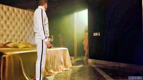 Seth in white tracksuit watching Kylie enter bedroom door, teasing fun on gold bed