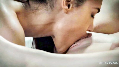 Brunette passionately licks glistening wet pussy lips of nude girl on sheets
