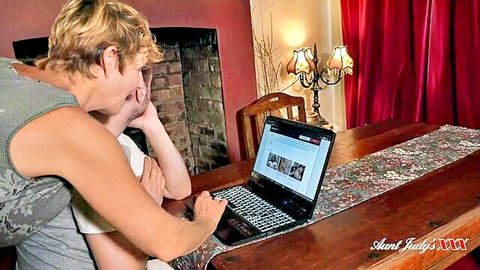Blonde MILF in tank top leaning over at laptop screen