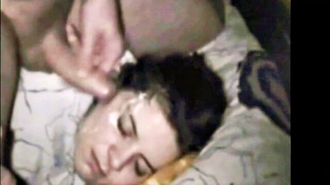Brunette teen lying on bed with thick cum facial covering her face and eyes after blowjob