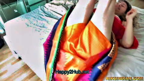Indian mature woman in colorful saree with legs raised on bed